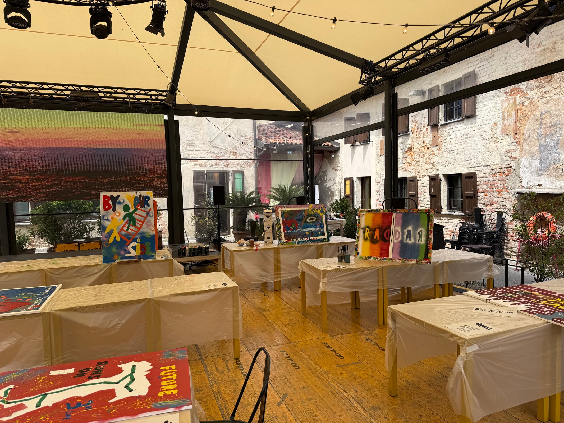 Workshop room prepared with tables, canvases and materials for a large team activity.